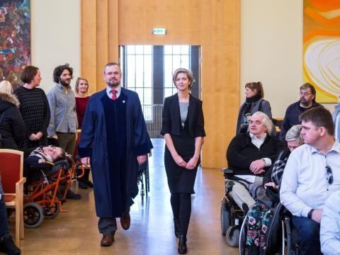 Daði Már Kristófersson sviðsforseti Félagsvísindasviðs og Ciara Brennan doktorskandídat ganga í hátíðasal í Aðalbyggingu HÍ.